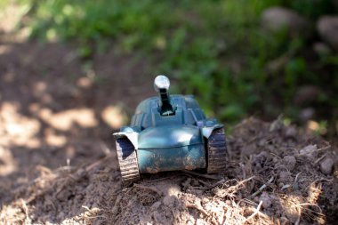 Oyuncak plastik tank yolda gidiyor ve sigara içiyor.