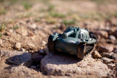 Oyuncak plastik tank yolda gidiyor ve sigara içiyor.