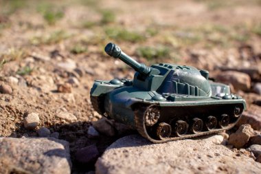 Oyuncak plastik tank yolda gidiyor ve sigara içiyor.