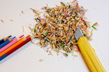  Renkli kalemler, beyaz bir arka plan ve kırtasiye bıçağı.