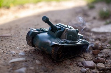 Oyuncak plastik tank yolda gidiyor ve sigara içiyor.