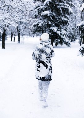 Karlı bir parkta bir kadın yürüyor..