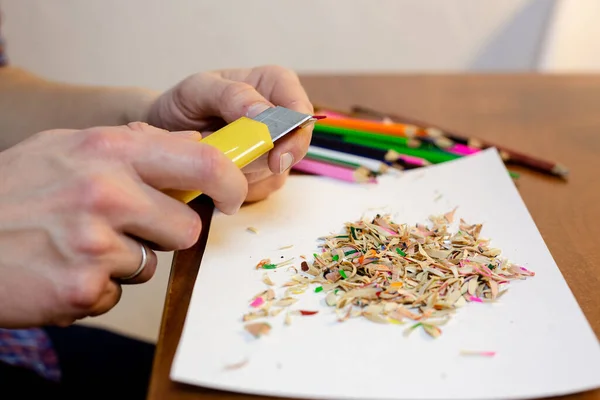 A man sharpens a pencil with a stationery knife — Stock Photo, Image