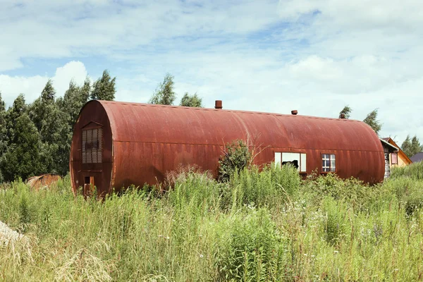Дом из старой ржавой цистерны, заросшей травой — стоковое фото