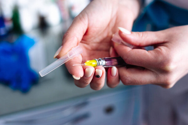 Female hands with a syringe for injection. Vaccination.
