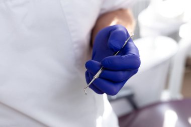 Mavi eldivenli erkek eller diş aletini tutuyor.