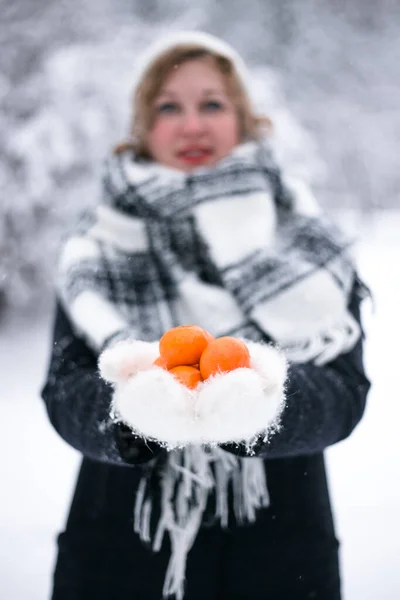 Vrouw blond in de winter met mandarijnen in handen Stockfoto