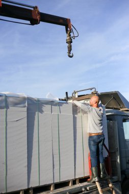 Vinç kullanarak bir kamyondan yapı taşlarını indiriyorum. Hidrolik düzenleyici.