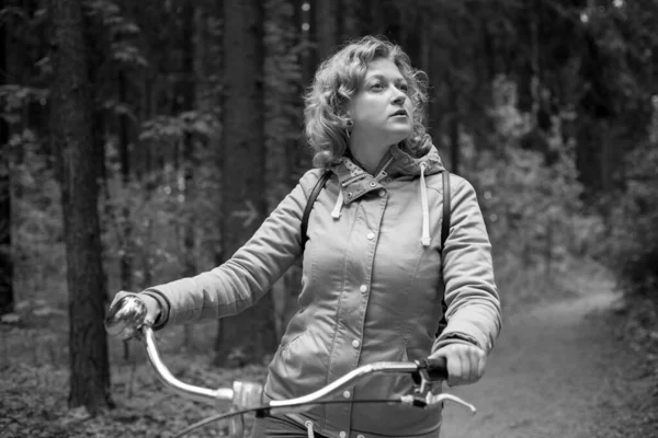 Una mujer rubia camina por el bosque con una bicicleta. Negro y whait foto. — Foto de Stock