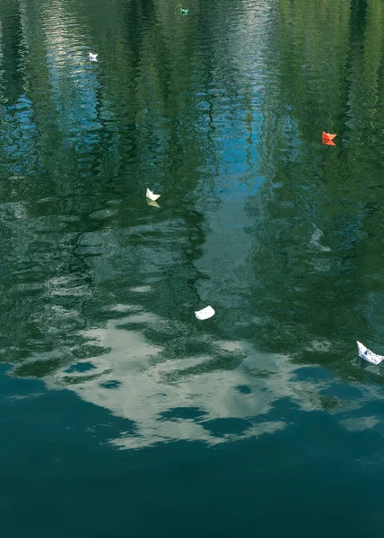 Many paper boats float on the water. Origami.