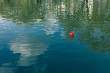 Kırmızı ve beyaz kağıt tekneler suda yüzer.