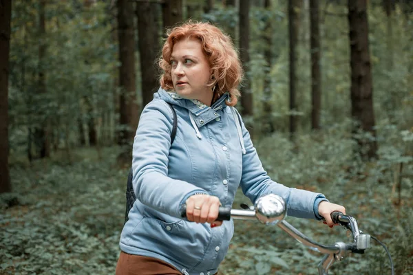 Mujer rubia con bicicleta en el bosque. — Foto de Stock