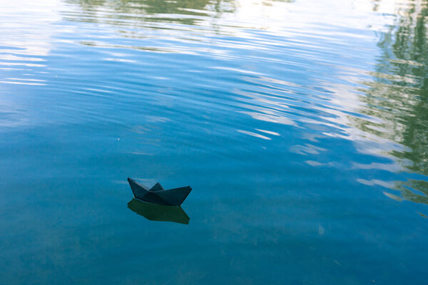 Black paper boat floats on the river