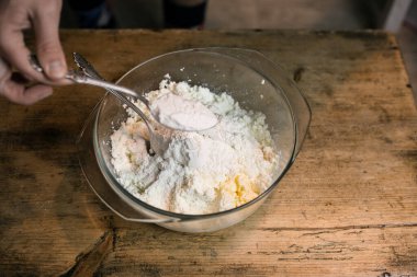 Kaşıklı bir kasede yumurtalarla süzme peyniri diz.