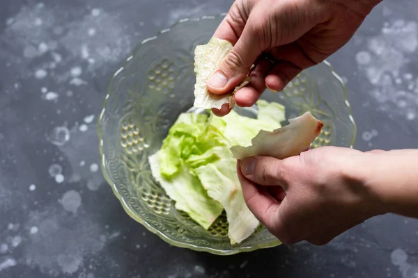 O homem rasga as folhas com as mãos em uma salada. Preparação da salada. — Fotografia de Stock