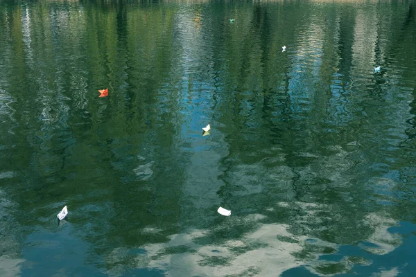 Many paper boats float on the water. Origami.