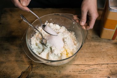 Kaşıklı bir kasede yumurtalarla süzme peyniri diz.