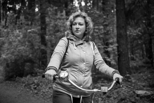 Mujer rubia con bicicleta en el bosque. Negro y whait foto. — Foto de Stock