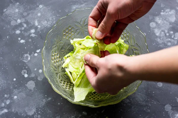 O homem rasga as folhas com as mãos em uma salada. Preparação da salada. — Fotografia de Stock