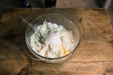 Kaşıklı bir kasede yumurtalarla süzme peyniri diz.