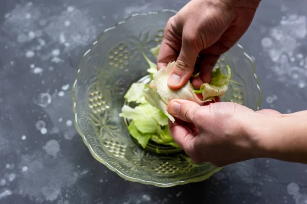 O homem rasga as folhas com as mãos em uma salada. Preparação da salada. — Fotografia de Stock
