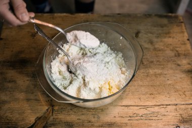 Kaşıklı bir kasede yumurtalarla süzme peyniri diz.