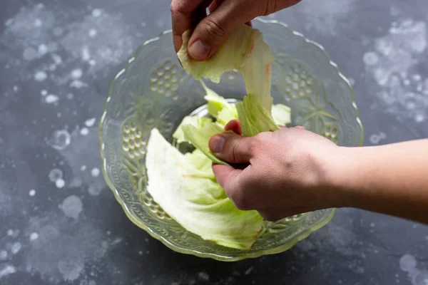 O homem rasga as folhas com as mãos em uma salada. Preparação da salada. — Fotografia de Stock