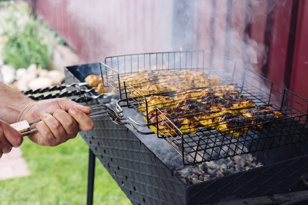 Hand roteert een spiesje met een kebab op de grill — Stockfoto