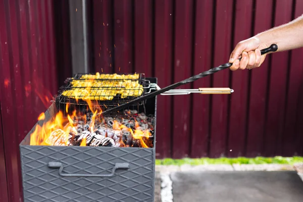 Ha valaki piszkavasat használ, kiegyenesíti a szenet a grillben. — Stock Fotó