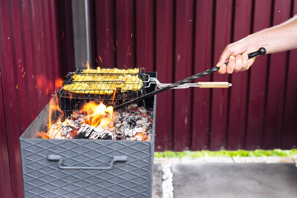 Een man met behulp van een poker rechtzet de kolen in de grill — Stockfoto