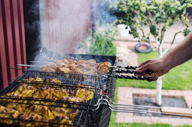 El ızgarasında kebap olan bir şişi döndürür.
