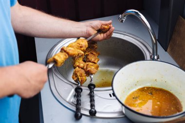 Aşçı yemek pişirmek için şişlere et diziyor.