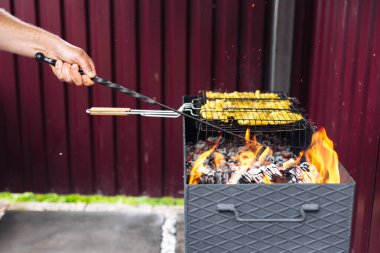 Poker kullanan bir adam ızgaradaki kömürleri düzeltir.