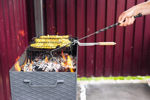 A man using a poker straightens the coals in the grill — 图库照片