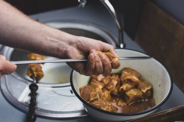 Aşçı yemek pişirmek için şişlere et diziyor.