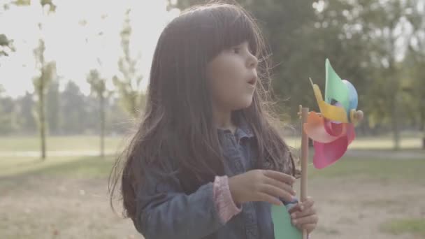 Χαριτωμένο κορίτσι της Λατινικής παίζει με ανεμιστήρα χαρτί και φυσάει σε αυτό — Αρχείο Βίντεο