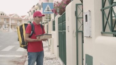 Üniformalı kurye kapı zili çalıyor, müşteriye paket veriyor.