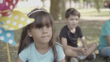 Latin uzun saçlı kız yerde oturuyor ve elinde kağıt yelpaze tutuyor.