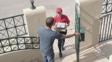 Üniformalı kurye kız müşteri kapısına paket getiriyor.