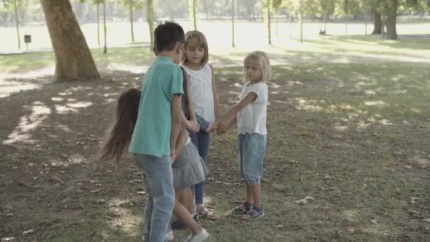 Niños felices de pie, tomados de la mano y jugando juego — Vídeos de Stock