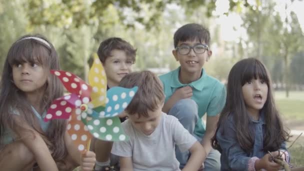 Група багатоетнічних дітей, які сидять разом на уроці під відкритим небом — стокове відео