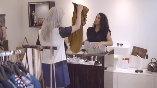 Femme aux cheveux blonds acheter des vêtements dans un magasin de mode — Video