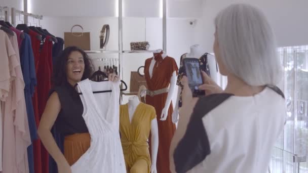 Mujer latina alegre eligiendo ropa en la tienda de moda — Vídeo de stock