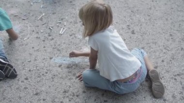 Sarışın bir kızın asfaltta oturup resim çizmesinin arkası.