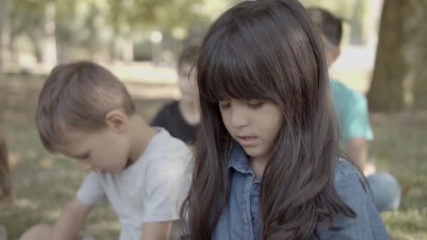 Härlig latinsk flicka sitter på marken med vänner — Stockvideo