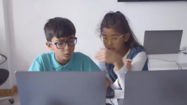 Gözlüklü birkaç ciddi sınıf arkadaşı proje üzerinde çalışıyor.