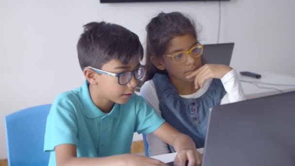 Пара школьников в очках, работающих над заданием — стоковое видео