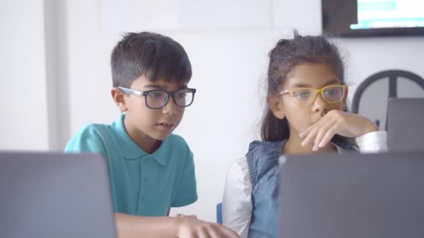 Мальчик и девочка в очках сотрудничают на классном проекте — стоковое видео