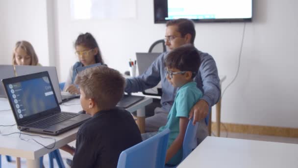 Преподаватель информатики помогает учащимся с заданием — стоковое видео