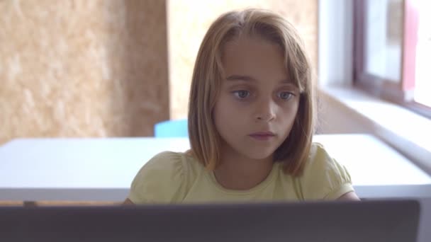 漂亮的女学生坐在课桌前，手里拿着笔记本电脑 — 图库视频影像
